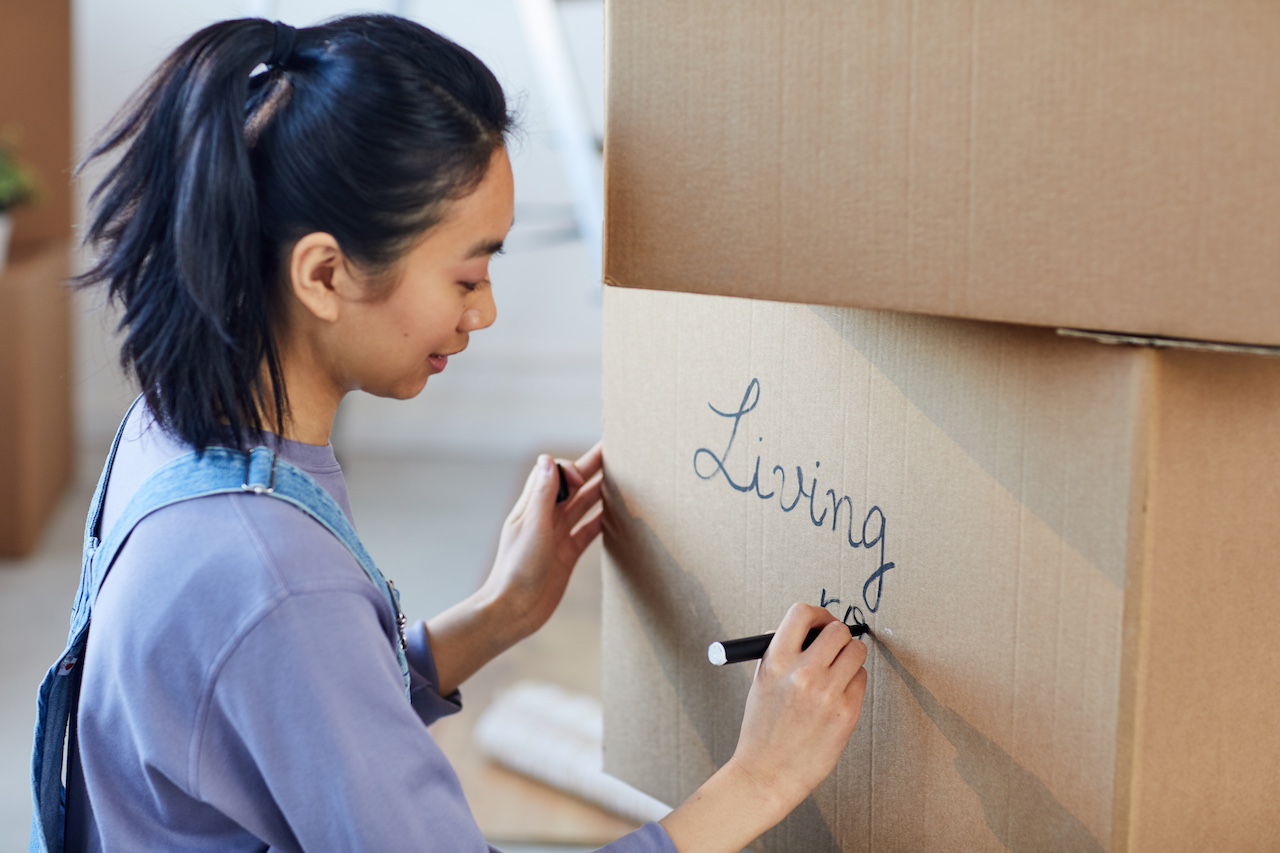 young woman labeling box for a local storage unit