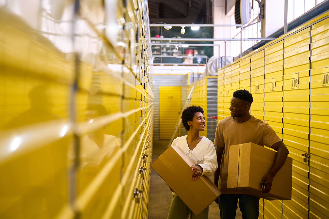 two people carry boxes in an indoor storage unit facility