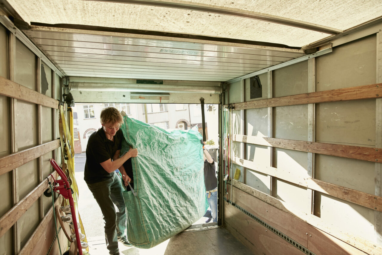 Two people use packing and moving tips to load mattress into truck