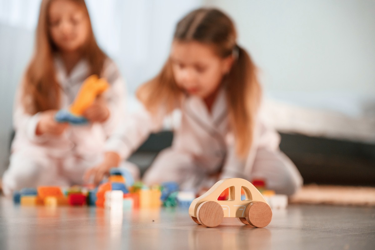 Kids playing with wooden toys on ground