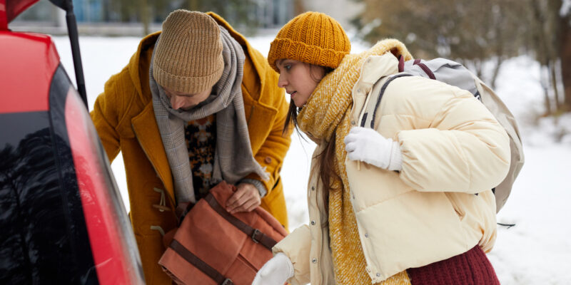 A couple packing a car trunk in the winter snow